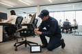 GLSC service technician adjusting a Herman Miller Aeron chair in an active corporate office, with a tablet showing a service ticket on the floor beside them