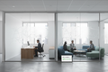 DIRTT floor-to-ceiling glass wall installation in a corporate office separating a private executive office from a collaborative lounge area, with a tablet showing DIRTT Feasibility Recommended
